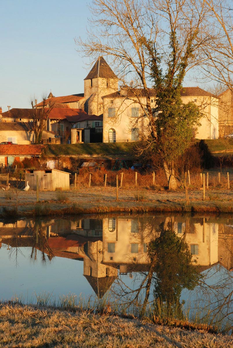 Village pittoresque et église reflétés dans l'eau.