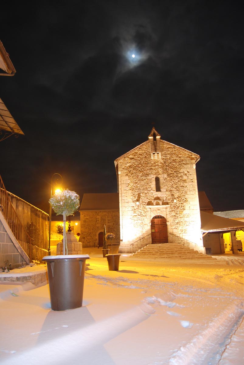Église illuminée la nuit sous la neige et lune.