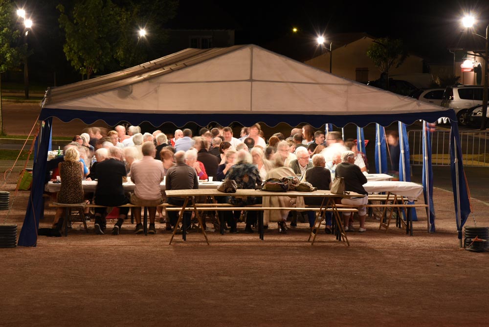 Fête nocturne sous tente avec de nombreux convives.