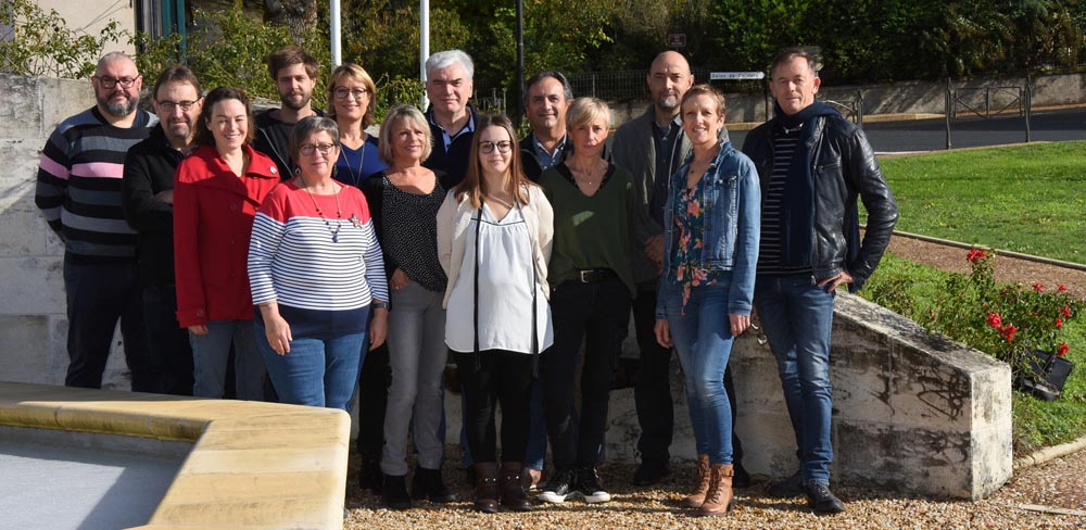 Groupe de personnes posant devant un mur extérieur.