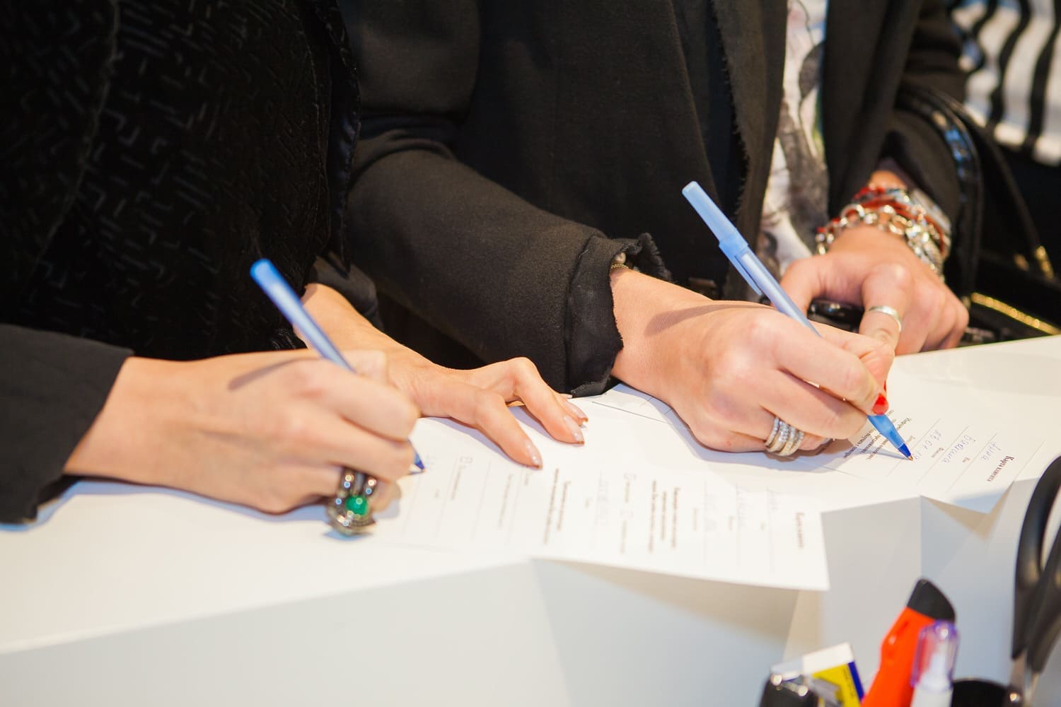 Personnes signant des documents avec stylos.